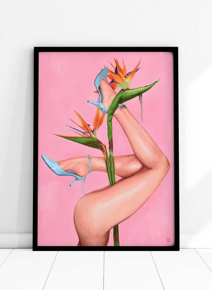 Legs wearing blue high heels with a pink background and bird of paradise flower. Bird of Paradise by Alexander Grahovsky art print featuring crossed legs in blue heels and a bold tropical flower on a pink background. Officially licensed surreal wall poster.