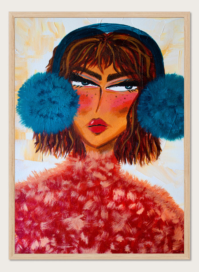 A stylized portrait painting of a woman with brown hair, a dark blue head covering, large bright blue pom-pom ear muffs, and a textured red fuzzy garment, set against a warm cream background. Shop Sassy Earmuffs Portrait by Amy Straley, a contemporary figurative wall art print featuring a bold woman portrait, blue earmuffs, and vivid pink and red tones.