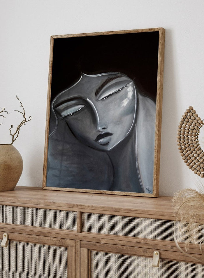 Artistic depiction of a stylized face with long hair on a dark background. Serene Woman Portrait by Amy Straley is a contemporary figurative art print featuring a monochromatic female portrait in soft grey and silver tones.