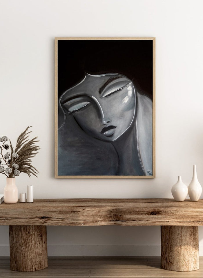 Artistic depiction of a stylized face with long hair on a dark background. Serene Woman Portrait by Amy Straley is a contemporary figurative art print featuring a monochromatic female portrait in soft grey and silver tones.