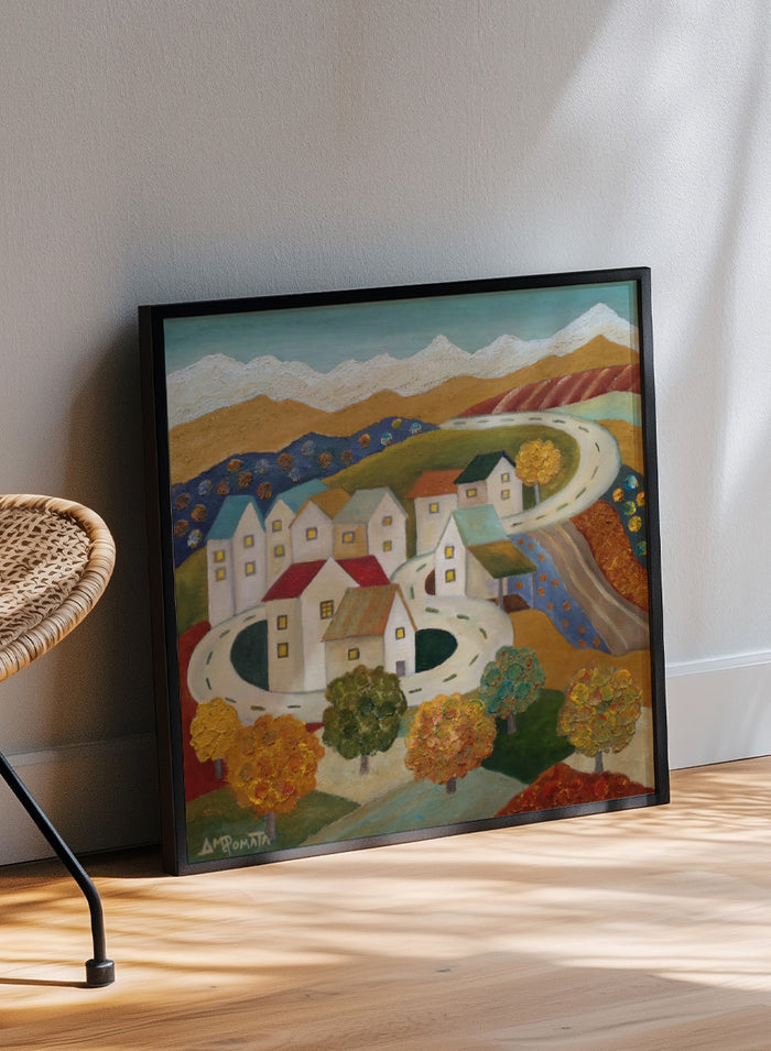 A framed folk-art style landscape painting depicting a village with white houses, winding roads, colorful trees, and mountains under a blue sky. Shop Autumn Road Village by Angeles M. Pomata, a colorful autumn landscape art print featuring a winding road, white village houses, fall trees, and distant mountains.