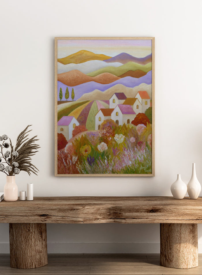 A colorful landscape painting featuring rolling hills, stylized houses, cypress trees, and wildflowers in the foreground, rendered in a painterly impressionistic style. Shop Colorful Countryside Village by Angeles M. Pomata, an autumn landscape art print featuring white houses, rolling hills, wildflowers, and warm earthy tones.