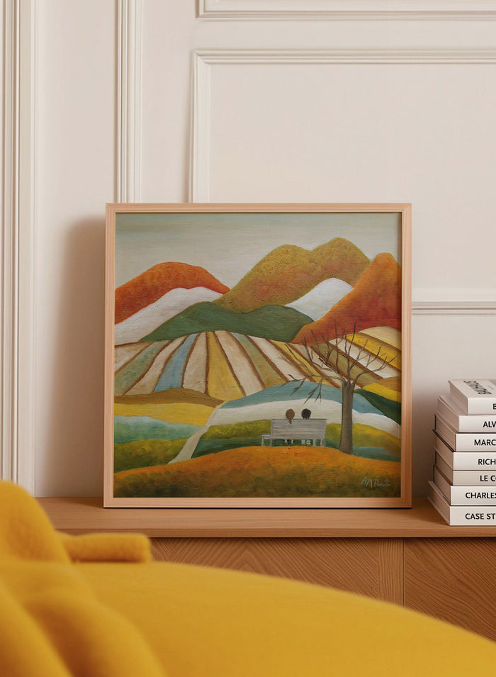 A framed landscape painting featuring stylized mountains, striped fields, a bench with two figures, and a bare tree. Shop Couple On Autumn Bench by Angeles M. Pomata, an autumn landscape and figurative art print featuring a seated couple, rolling hills, patchwork fields, and warm fall tones.