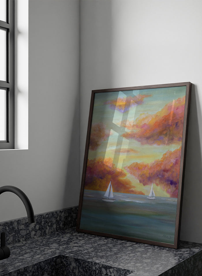 A framed painting of two white sailboats on a calm blue-green sea under a sky filled with soft, painterly clouds in pink, orange, yellow, and purple tones. Shop Sailboat Sunset Sky by Angeles M. Pomata, a coastal landscape art print featuring sailboats, calm water, and a glowing sunset sky.