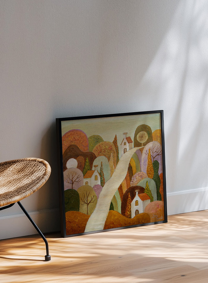 A framed landscape painting featuring stylized white houses, a winding cream path, and rolling hills in earthy tones of brown, orange, green, and purple. Shop Whimsical Village Path by Angeles M. Pomata, an autumn landscape art print featuring a winding road, white village houses, rounded hills, and warm earthy tones.