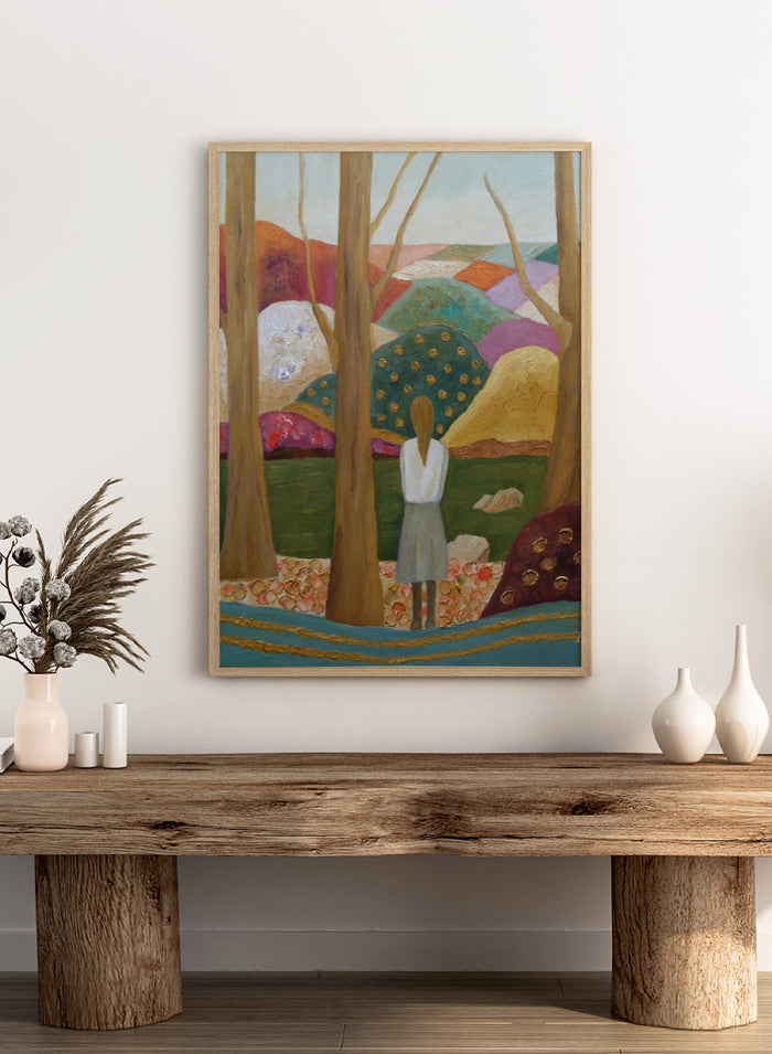 An expressive painting of a woman seen from behind standing among tall trees in a stylized landscape with colorful hills, patches of green, purple, pink, blue, and gold accents. Shop Woman Among Vibrant Hills by Angeles M. Pomata, a colorful landscape and portrait art print featuring a woman, rolling hills, trees, and earthy tones.