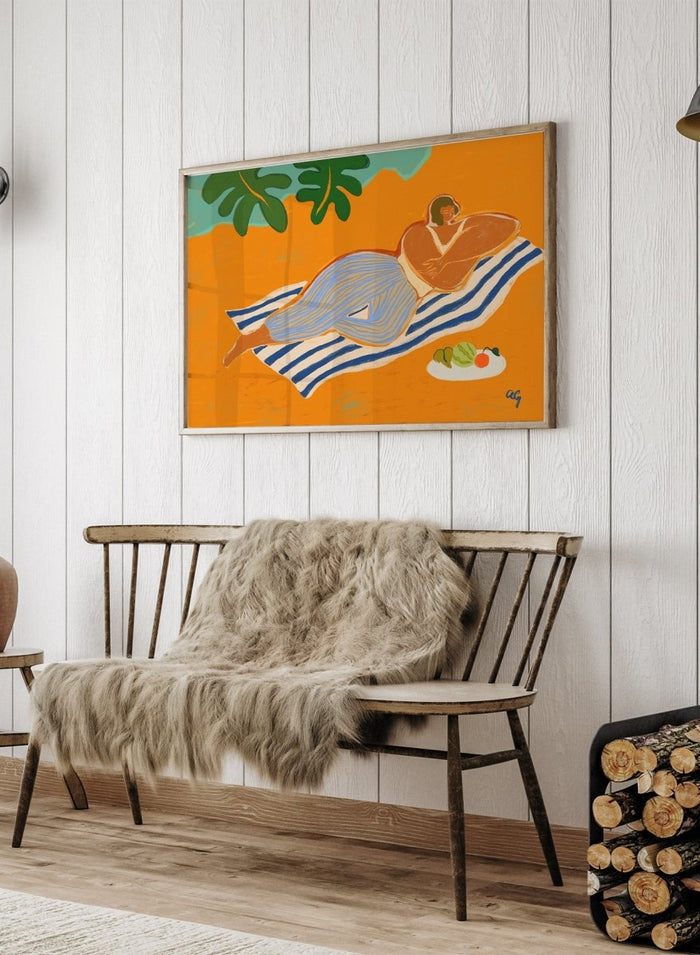 Framed artwork of a woman lounging on a towel with a plate of fruit against an orange background. A Day at the Beach by Arty Guava is a colorful coastal art print featuring a relaxed beach scene, tropical foliage, bold color, and contemporary illustration.