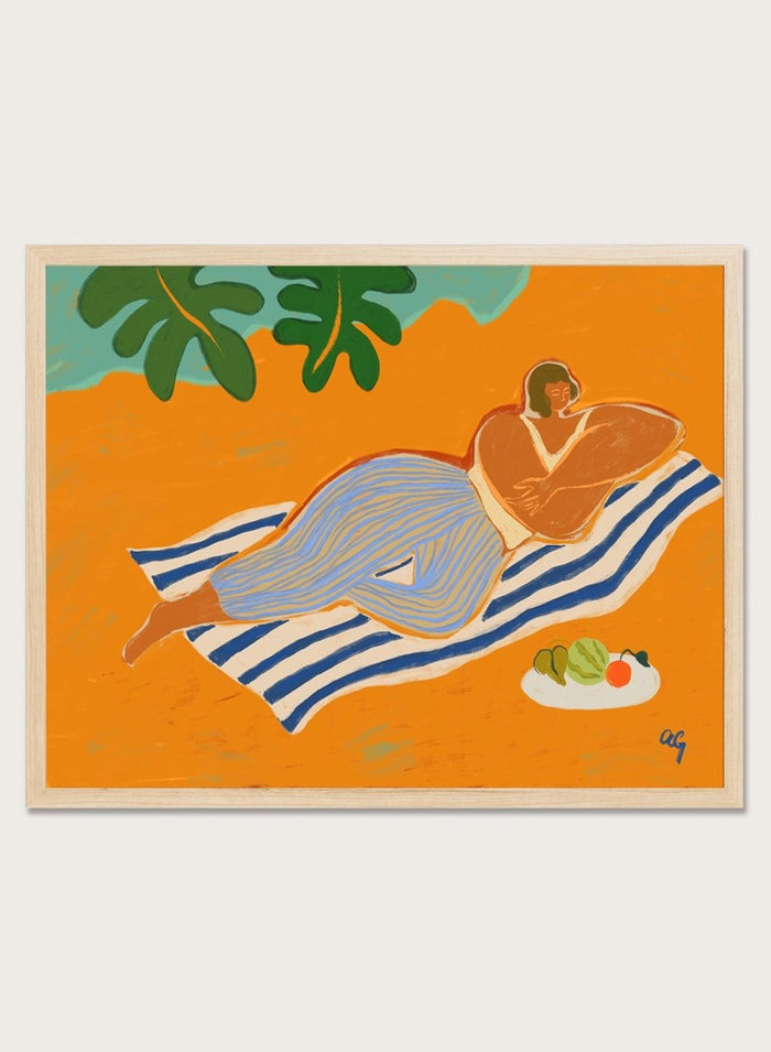 Framed artwork of a woman lounging on a towel with a plate of fruit against an orange background. A Day at the Beach by Arty Guava is a colorful coastal art print featuring a relaxed beach scene, tropical foliage, bold color, and contemporary illustration.