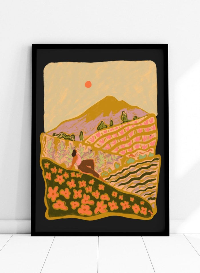 Illustration of a person sitting on a hill with a mountain and sunset in the background. Field Of Flowers by Arty Guava is a colorful landscape art print featuring blooming fields, rolling hills, nature-inspired illustration, and contemporary wall art.