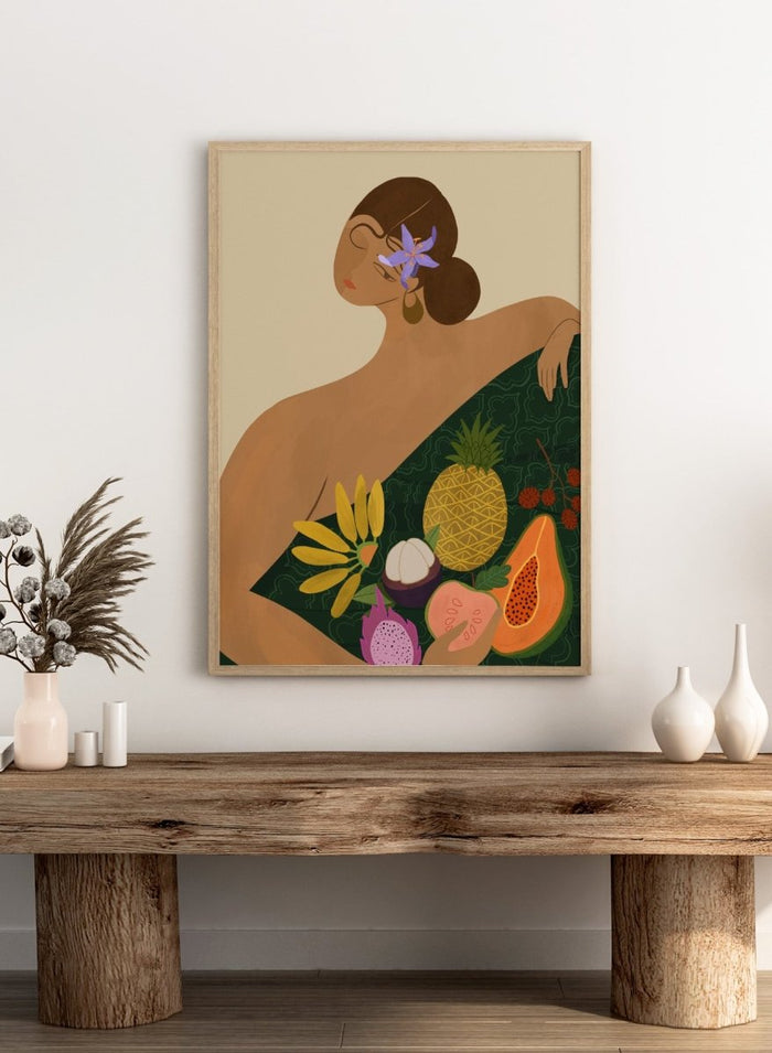 Illustration of a woman with a green wrap featuring tropical fruits on a beige background. Fruit Seller by Arty Guava is a colorful tropical art print featuring exotic fruit, expressive female figures, bold color, and contemporary illustration.