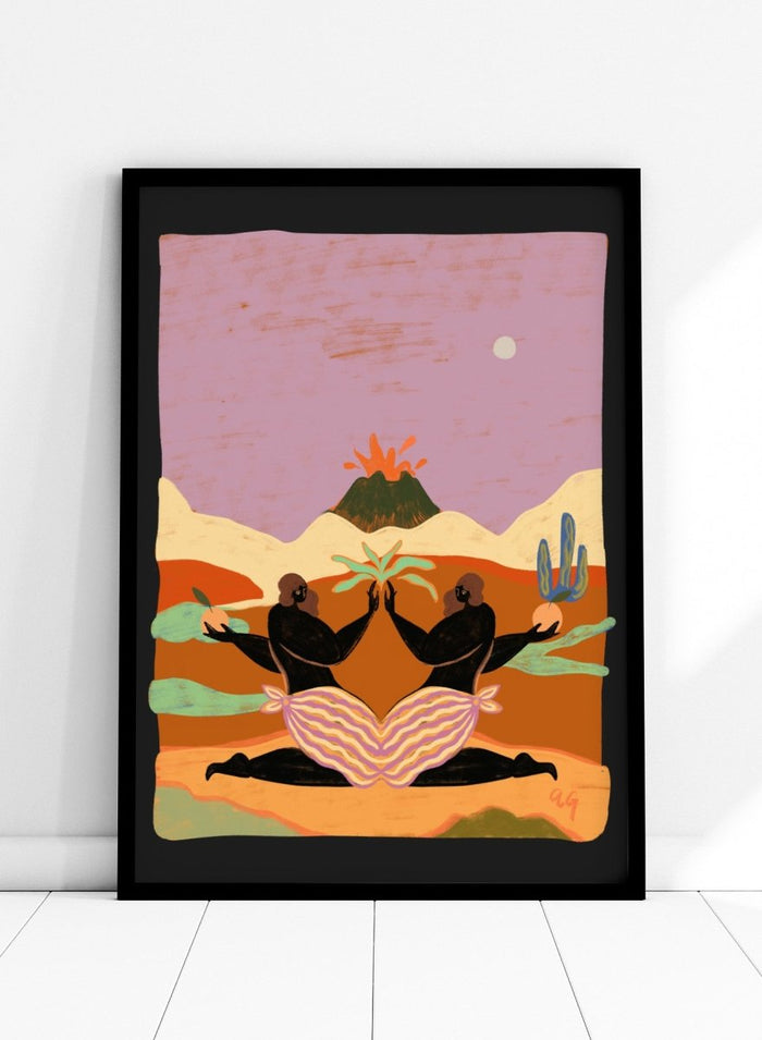A framed art print featuring a stylized desert landscape with two black silhouetted figures seated in a lotus position, facing each other beneath a volcano and cacti, set against a pink sky. Lava by Arty Guava premium framed fine art print featuring mirrored women, tropical plants, and a glowing volcano in bold, surreal colors.