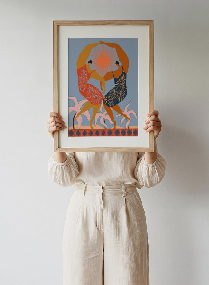 Artistic depiction of two dancers with a sun in the center on a blue background. Sisterhood by Arty Guava is a modern art print of two women dancing under the sun, celebrating friendship and unity. Officially licensed wall poster.