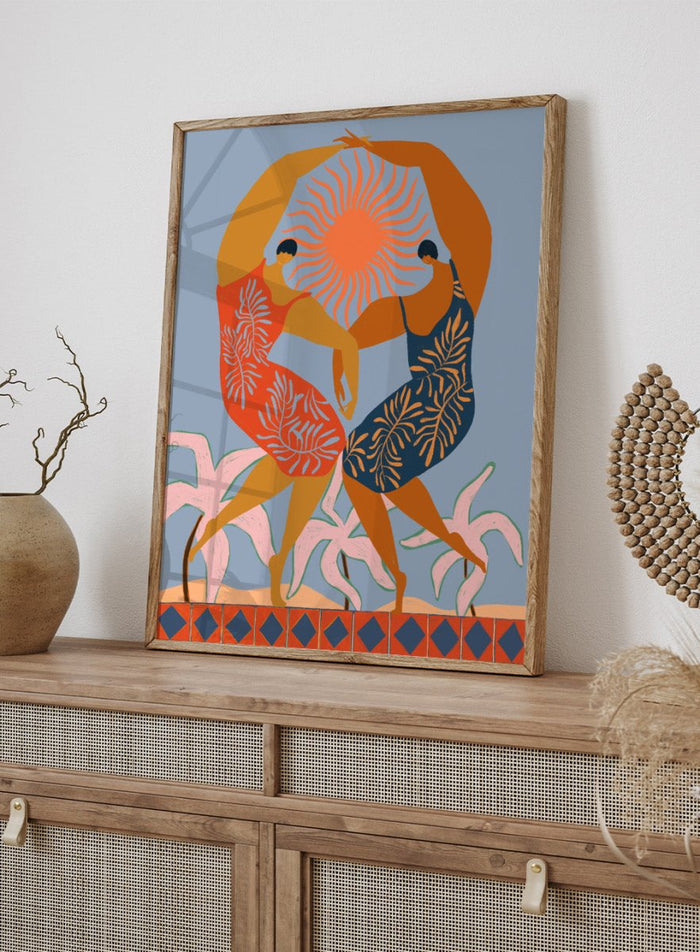 Artistic depiction of two dancers with a sun in the center on a blue background. Sisterhood by Arty Guava is a modern art print of two women dancing under the sun, celebrating friendship and unity. Officially licensed wall poster.