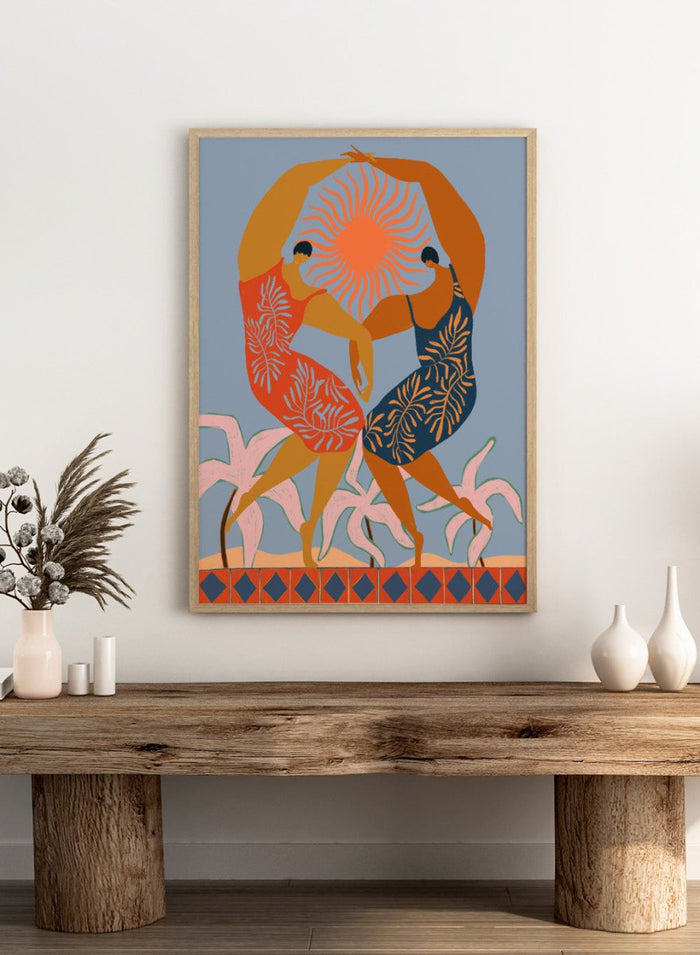 Artistic depiction of two dancers with a sun in the center on a blue background. Sisterhood by Arty Guava is a modern art print of two women dancing under the sun, celebrating friendship and unity. Officially licensed wall poster.