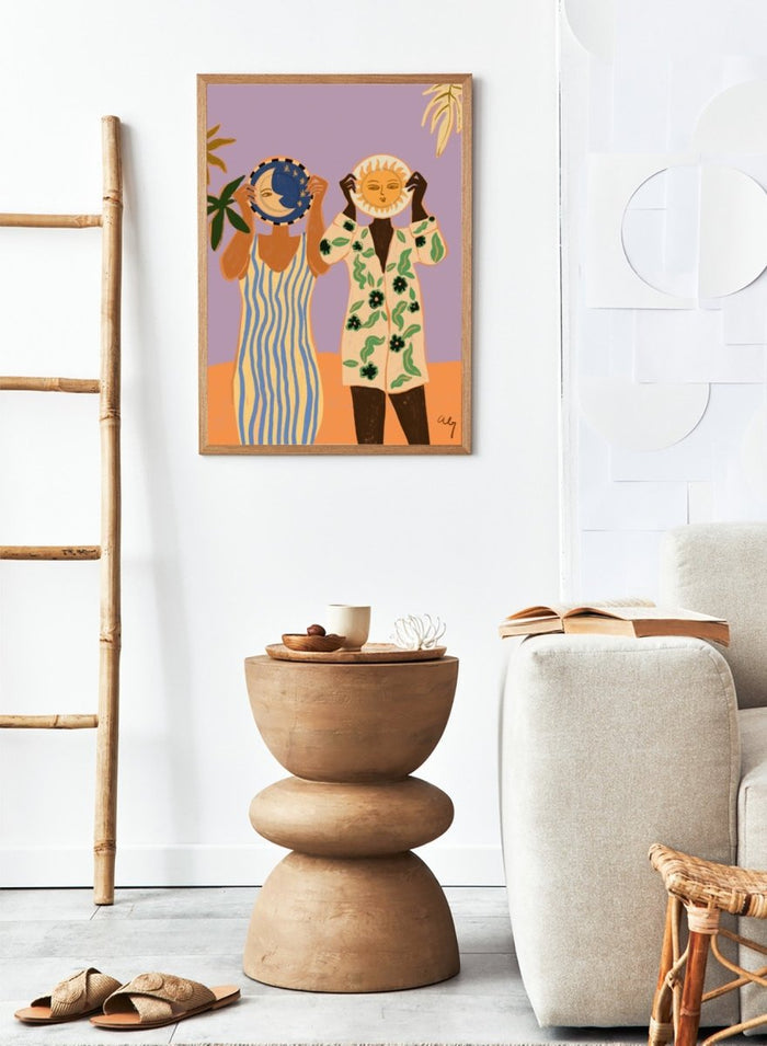 Two people holding celestial objects against a purple background. Sun and Moon by Arty Guava is a playful contemporary art print featuring female figures, celestial motifs, bold color, tropical influences, and modern illustration.