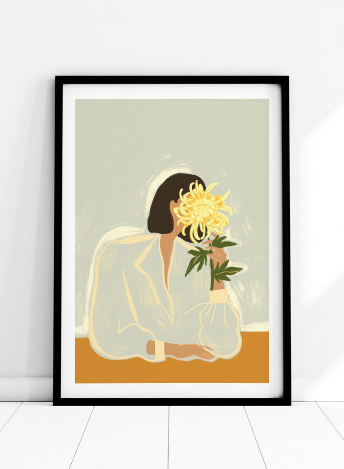 Illustration of a woman in a white dress holding a large yellow flower against a light background. The Chrysanthemum by Arty Guava is a modern portrait illustration featuring a woman with flowers, contemporary floral wall art style, and officially licensed artwork.