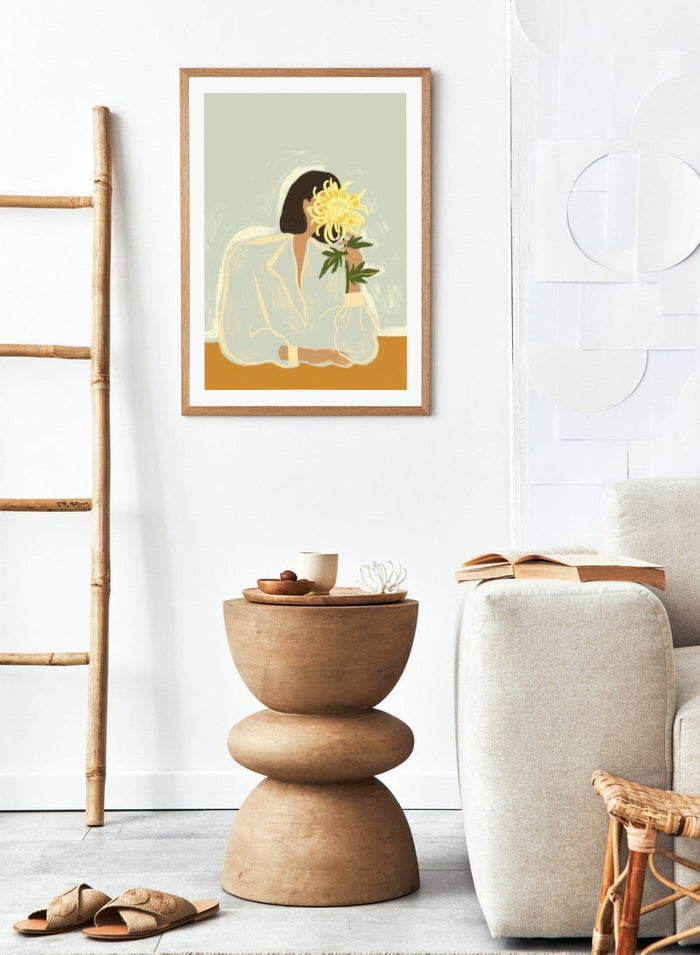 Illustration of a woman in a white dress holding a large yellow flower against a light background. The Chrysanthemum by Arty Guava is a modern portrait illustration featuring a woman with flowers, contemporary floral wall art style, and officially licensed artwork.