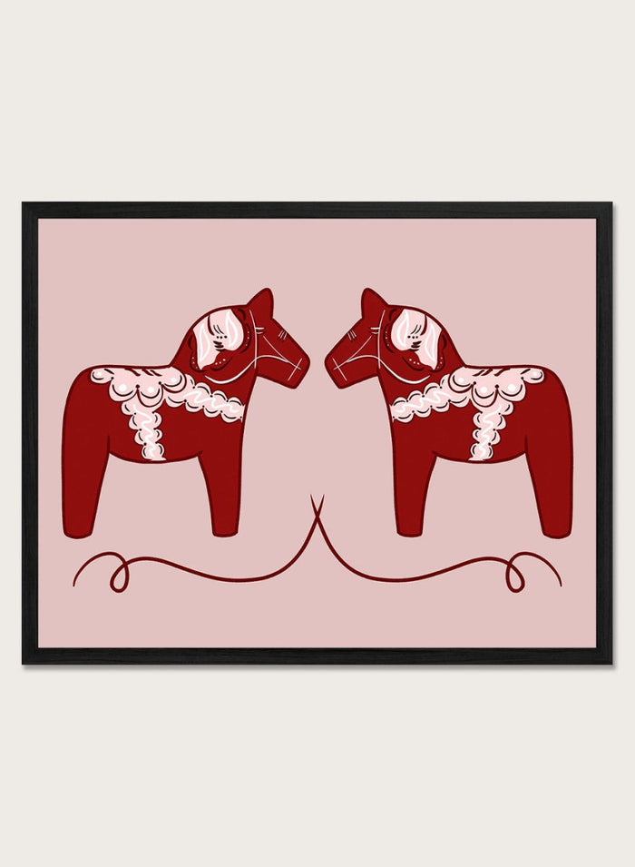 Two red Dala horse figures with white patterns on a pink background. Nordic Horses Twins by Athene Fritsch is a Scandinavian folk art illustration art print featuring Swedish Dala horses, bold red color, and modern wall art design.