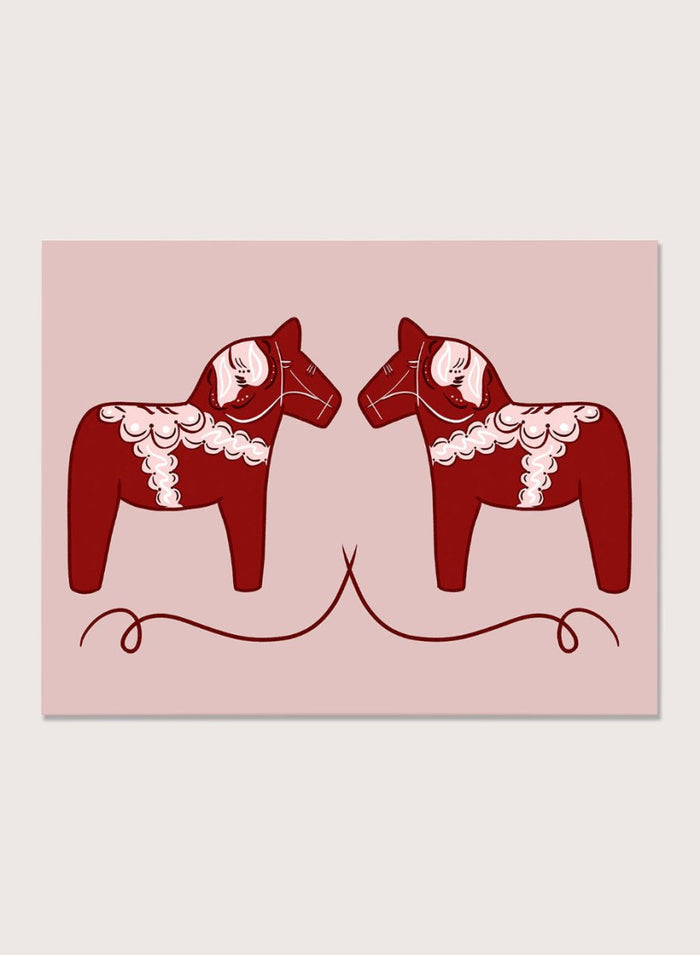Two red Dala horse figures with white patterns on a pink background. Nordic Horses Twins by Athene Fritsch is a Scandinavian folk art illustration art print featuring Swedish Dala horses, bold red color, and modern wall art design.