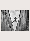 Superman by Azim Khan Ronnie black and white photography print of man jumping between trains in Bangladesh, urban action wall art poster