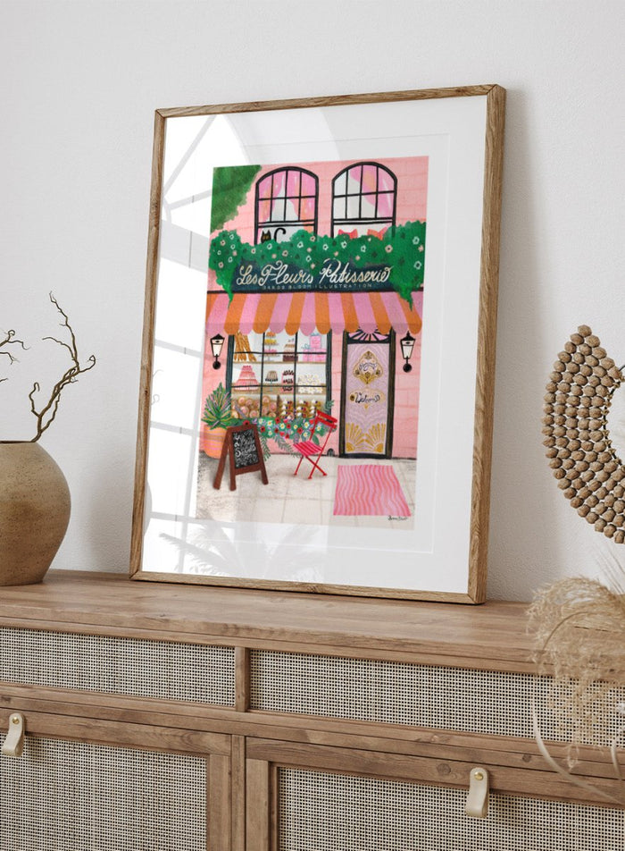 Illustration of a bakery named 'Les Fleuris Patisserie' with a pink exterior and greenery. Bake Shop Front by Baroo Bloom art print featuring a colorful bakery storefront illustration. Whimsical European street scene wall poster with pink tones and playful detail.