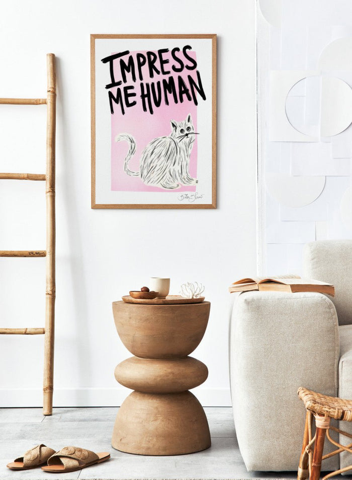 Cartoon cat with 'Impress Me Human' text on a pink background. Cat Owner. Impress Me Human by Baroo Bloom is a playful cat art print featuring hand-drawn illustration and humorous typography. Officially licensed wall poster with optional framing.
