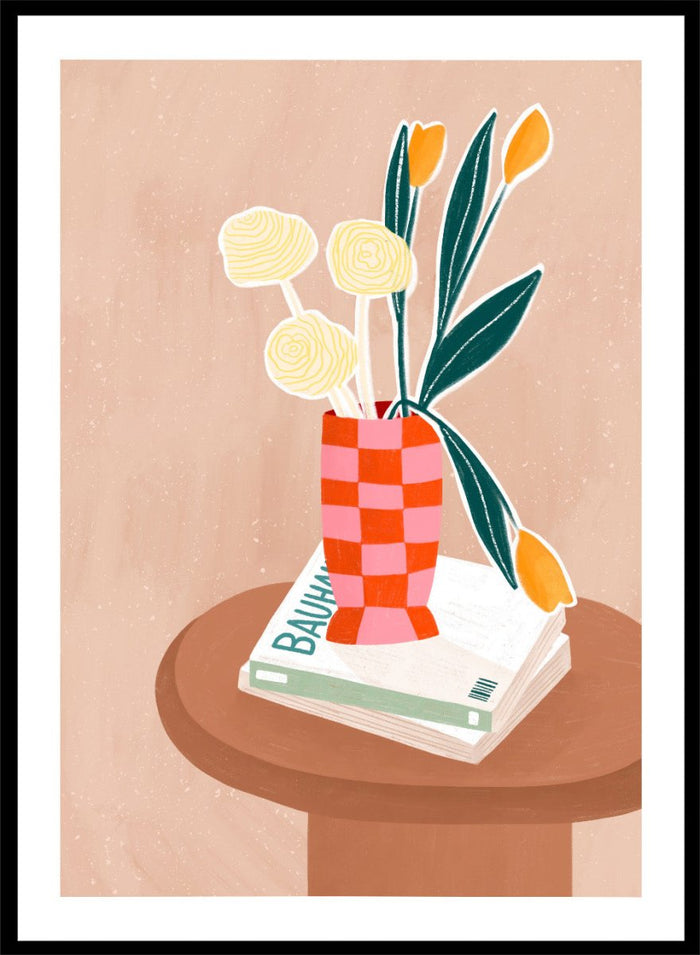 A framed minimalist art print featuring a stylized illustration of a pink and orange checkered vase filled with yellow and orange tulips, resting on a brown round table next to a white book. Colorful Tabletop Flowers by Bea Müller premium framed fine art print featuring yellow tulips and cream blooms in a red-and-pink checkered vase.