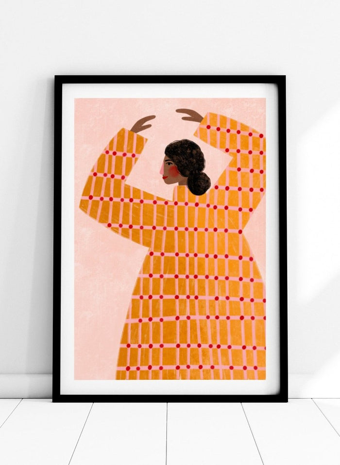 A framed art print featuring a stylized illustration of a woman in profile wearing a bright orange dress with a red grid pattern, set against a pale pink background. Dancing Woman in Orange by Bea Müller premium fine art print featuring a bold figure, warm orange tones, and a playful graphic composition.