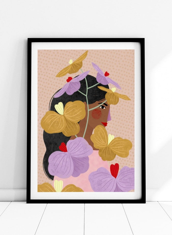 A framed art print featuring a stylized illustration of a woman with dark hair surrounded by large purple and yellow flowers on a beige patterned background. Floral Woman Portrait by Bea Müller premium framed fine art print featuring a woman surrounded by oversized lilac, mustard, and red flowers.