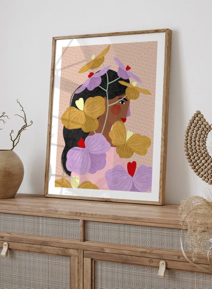 A framed art print featuring a stylized illustration of a woman with dark hair surrounded by large purple and yellow flowers on a beige patterned background. Floral Woman Portrait by Bea Müller premium framed fine art print featuring a woman surrounded by oversized lilac, mustard, and red flowers.