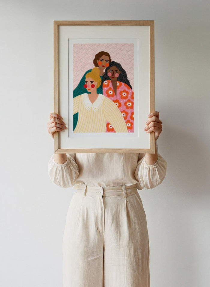 Illustration of three women with colorful clothing and patterns on a pink background. Girl Friends by Bea Müller is an officially licensed art print featuring three women illustrated in her signature bold colors and modern expressive style.