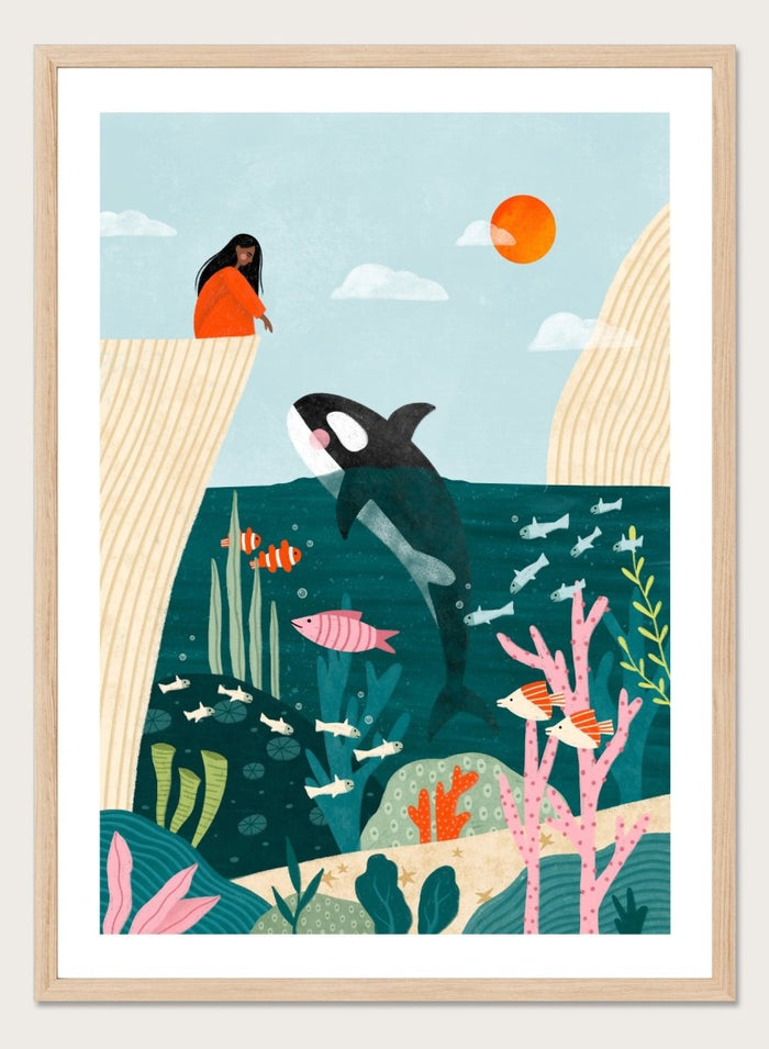 A framed art print featuring a whimsical underwater scene with an orca, coral, fish, and a woman in an orange dress standing on a cliff edge under a sun. Girl Watches Ocean Life by Bea Müller premium framed fine art print featuring a child watching an orca swim through a colorful underwater world.