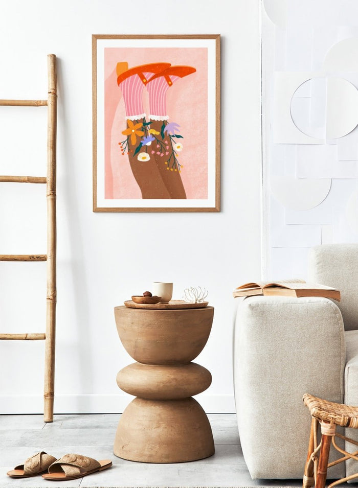 A stylized art print featuring a pair of legs wearing pink striped socks with white ruffles, decorated with colorful wildflowers, and topped with orange high-heeled shoes, set against a textured pink background. Happy Feet and Flowers by Bea Müller premium framed fine art print featuring red Mary Janes, striped socks, and colorful flowers on a soft pink background.