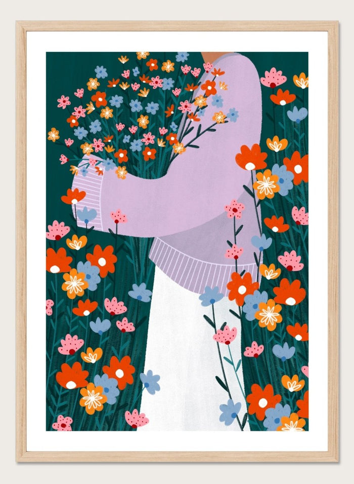 A stylized art print featuring a woman in a lavender sweater and white skirt holding a large bouquet of colorful wildflowers, framed by dense flowers on a dark teal background. Happy Woman Holding Flowers by Bea Müller premium framed fine art print featuring a woman carrying wildflowers in bright orange, pink, blue, and teal.