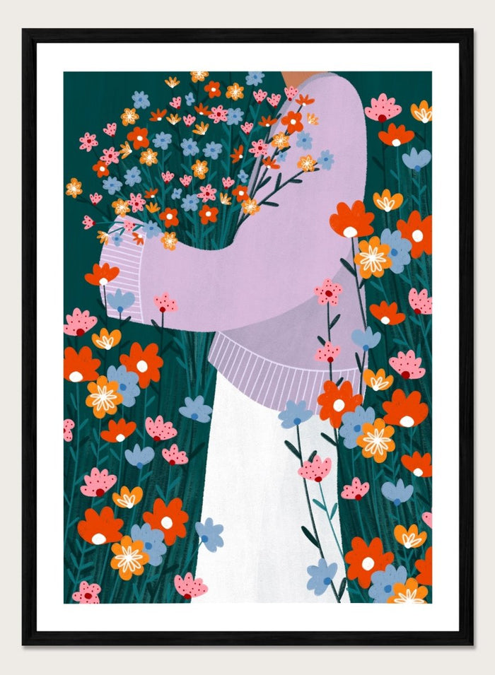 A stylized art print featuring a woman in a lavender sweater and white skirt holding a large bouquet of colorful wildflowers, framed by dense flowers on a dark teal background. Happy Woman Holding Flowers by Bea Müller premium framed fine art print featuring a woman carrying wildflowers in bright orange, pink, blue, and teal.