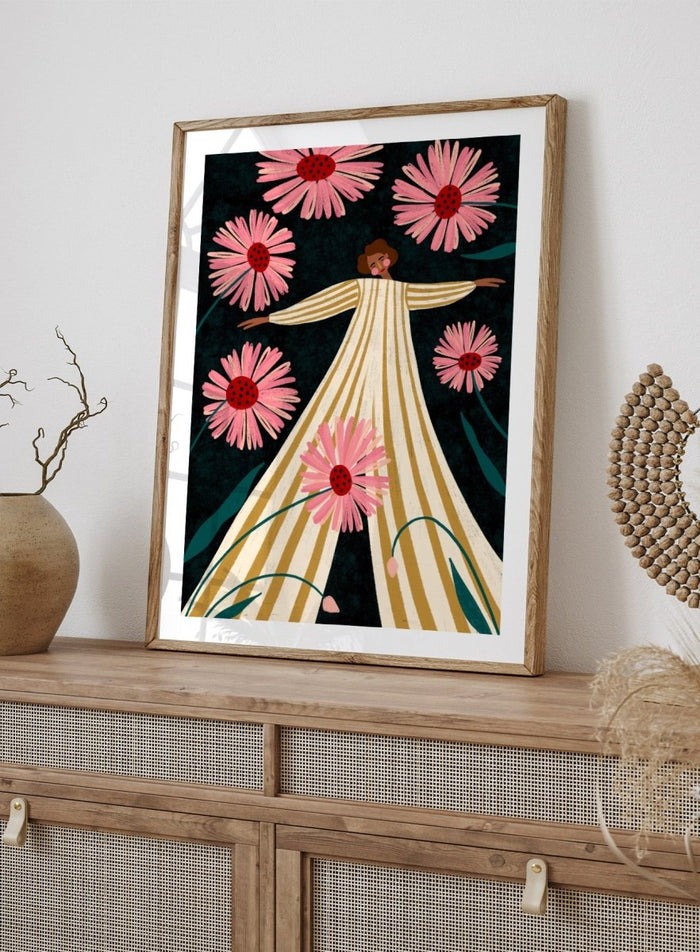 A framed art print featuring a stylized illustration of a woman in a cream and gold striped dress surrounded by large pink flowers on a dark background. Joyful Woman In Bloom by Bea Müller premium framed fine art print featuring a woman in a striped dress surrounded by oversized pink flowers.