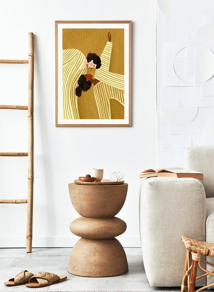 A framed art print featuring a stylized illustration of two women in cream and gold striped dresses against a textured gold background. Loving Embrace by Bea Müller premium fine art print featuring two figures in striped clothing, with warm colors and a bold, intimate composition.