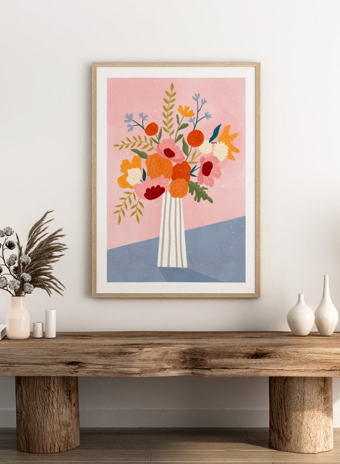 A framed art print featuring a colorful, stylized illustration of a flower bouquet in a striped vase against a pink and blue background. Modern Floral Arrangement by Bea Müller premium framed fine art print featuring a colorful bouquet in a striped vase on a soft pink background.