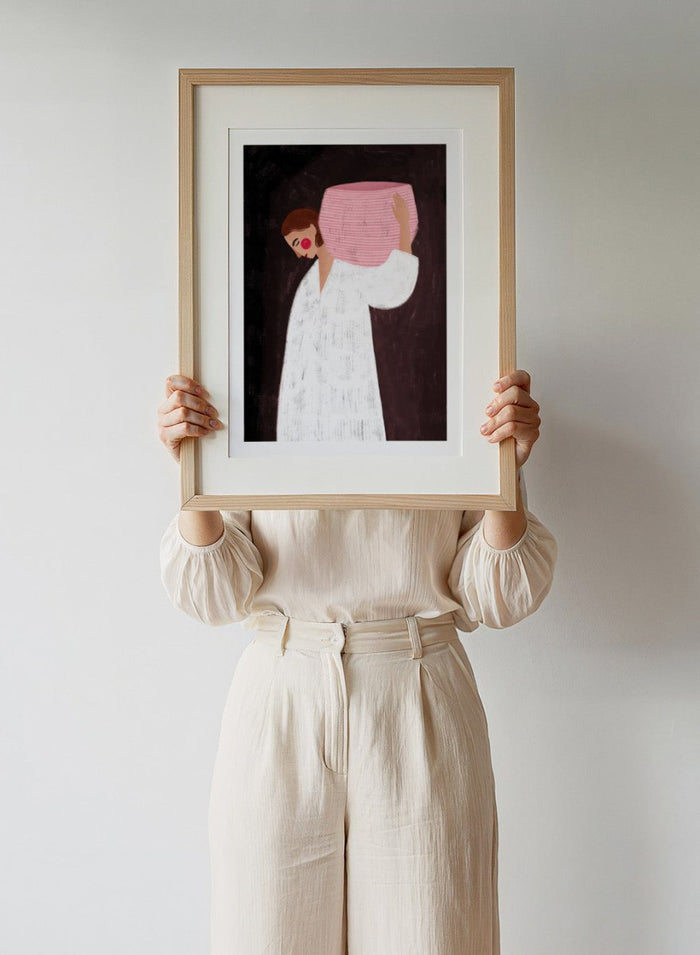 The Woman With the Pink Basket by Bea Müller is an officially licensed art print featuring a modern illustrated figure with soft color contrast and a calm, grounded feel. Available framed or unframed.