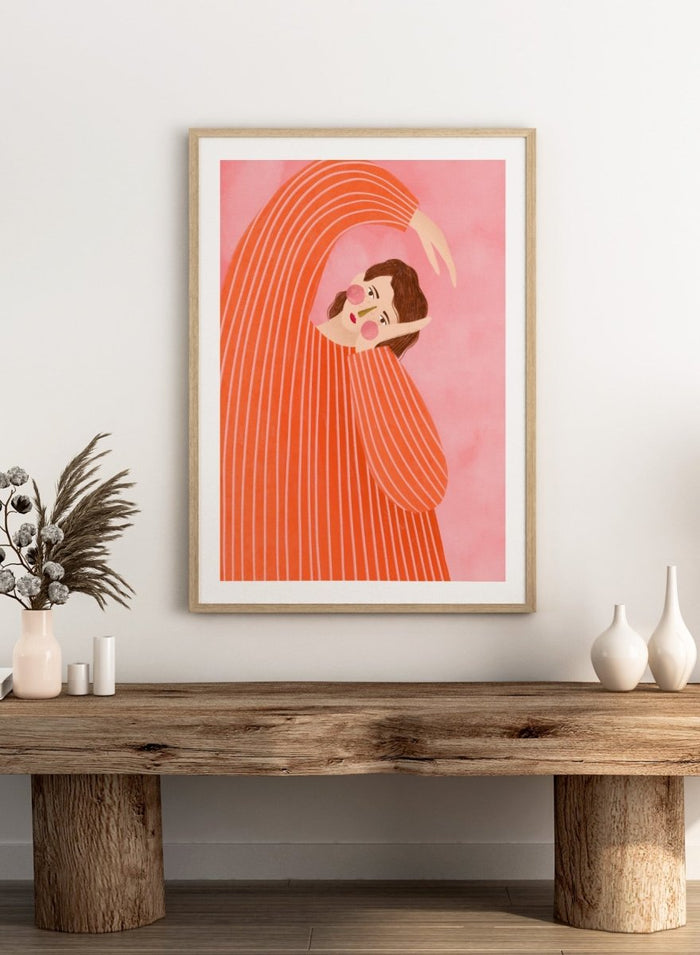 A framed art print featuring a stylized illustration of a woman in a flowing orange and white striped dress, posed in a graceful arch against a soft pink background. Thoughtful Girl in Stripes by Bea Müller premium framed fine art print featuring a woman in an oversized orange striped top against a soft pink background.