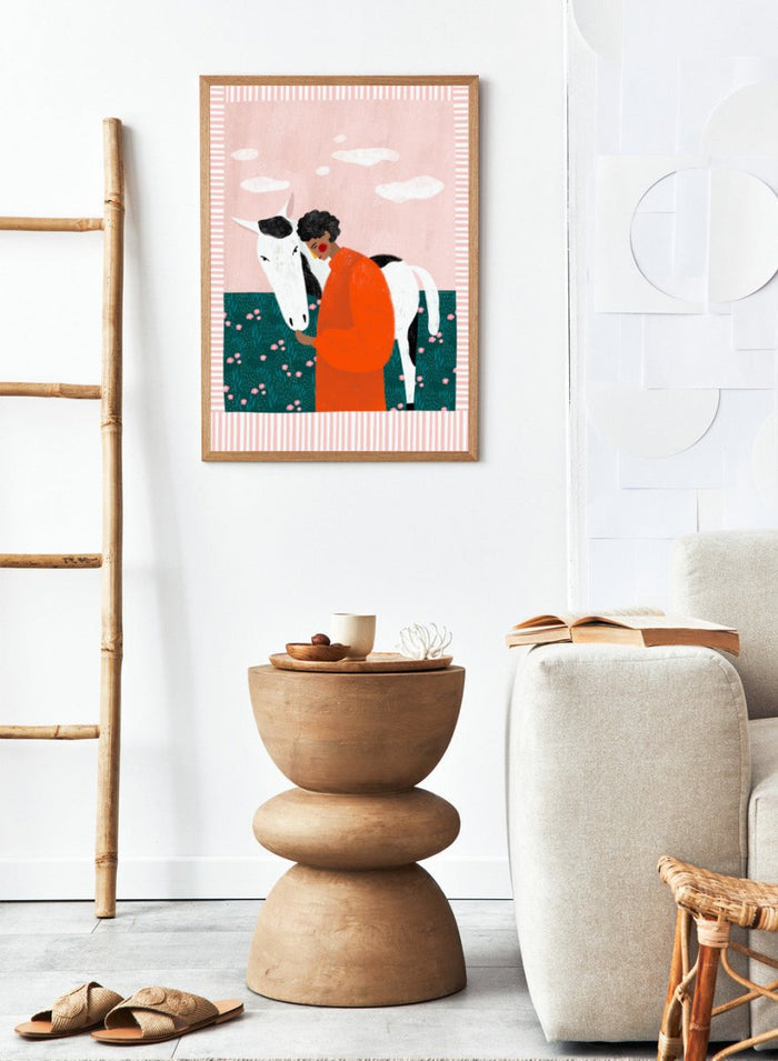 Illustration of a person in an orange outfit hugging a white horse against a pink background with clouds. Vibrant Girl and Horse by Bea Müller is a colorful girl and horse art print featuring modern expressive illustration. Officially licensed wall poster with optional framing.