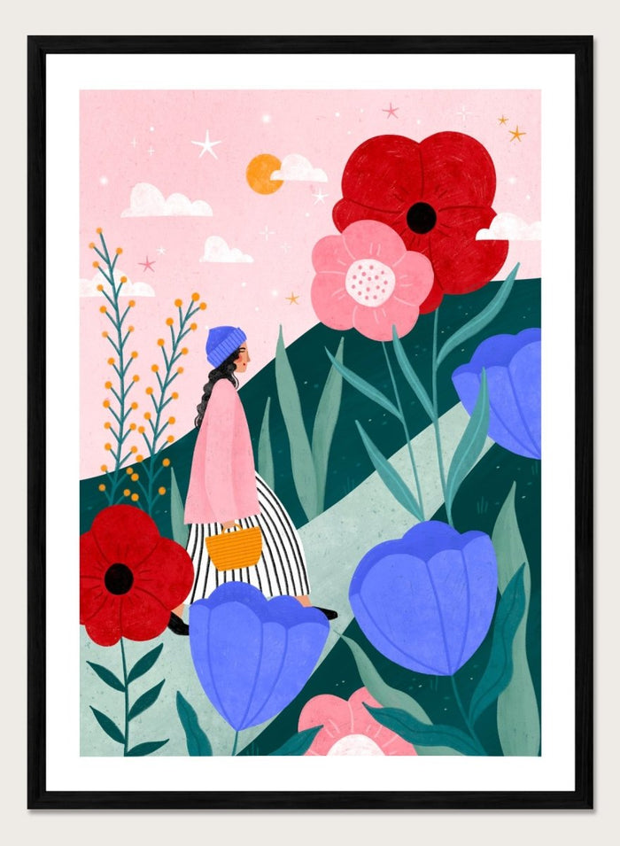 A framed art print featuring a whimsical, colorful illustration of a woman walking through a field of oversized flowers under a pink sky with moon. Whimsical Flower Path by Bea Müller premium fine art print featuring a woman walking among oversized flowers in a bright, playful landscape.