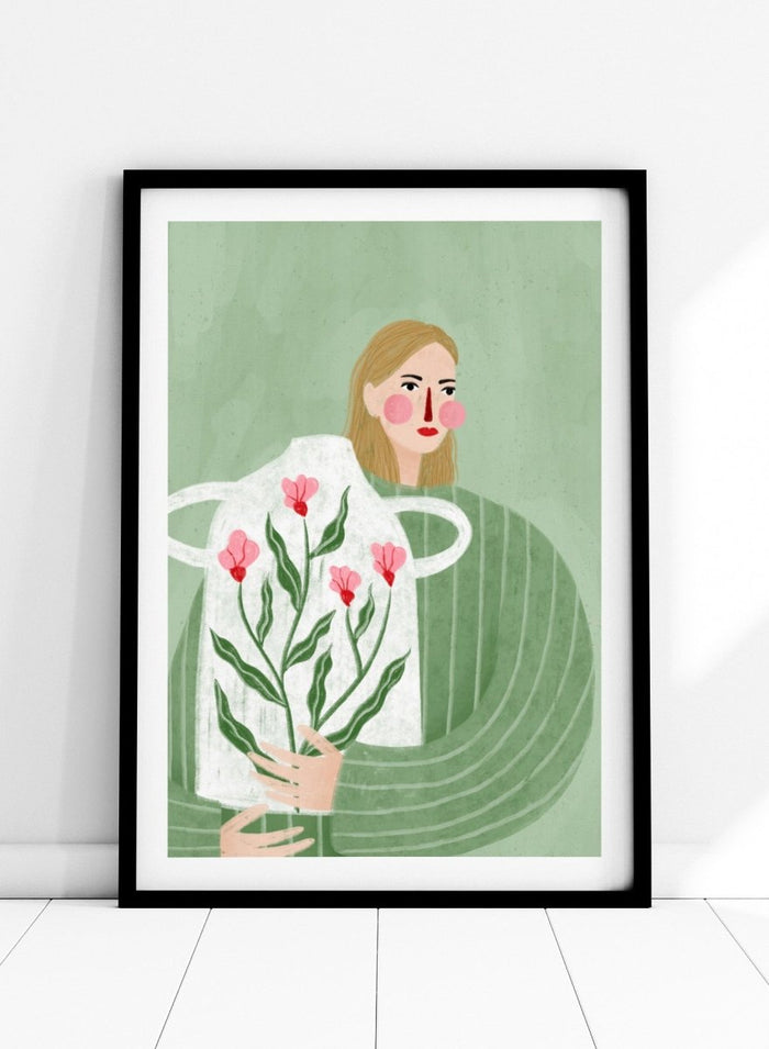 A framed art print featuring a stylized illustration of a woman with blonde hair holding a white apron decorated with pink flowers and green leaves, set against a sage green background. Woman Holding Flowers by Bea Müller premium framed fine art print featuring a woman carrying a white vase filled with pink flowers and green leaves.
