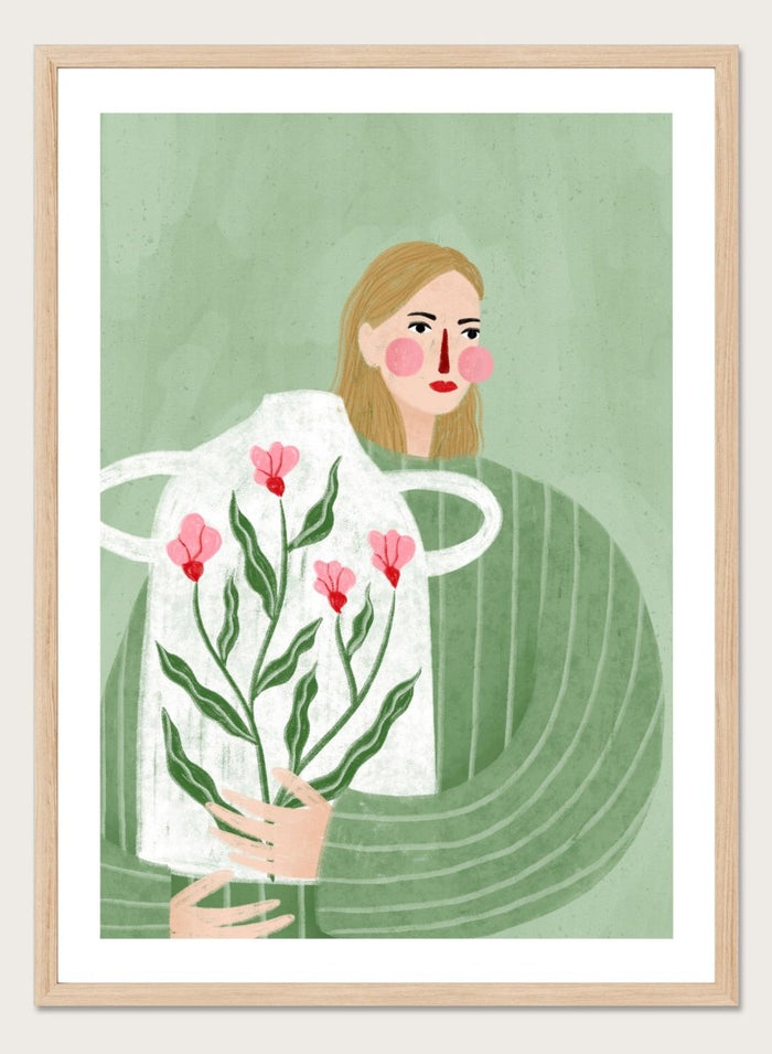 A framed art print featuring a stylized illustration of a woman with blonde hair holding a white apron decorated with pink flowers and green leaves, set against a sage green background. Woman Holding Flowers by Bea Müller premium framed fine art print featuring a woman carrying a white vase filled with pink flowers and green leaves.