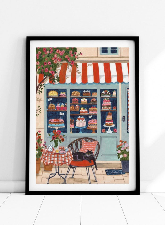 Illustration of a bakery with a cat sitting on a chair outside. Bakery Cat Cafe by Caroline Bonne Müller is a colorful bakery art print featuring cat illustration, pastry shop window, floral details, and modern aesthetic cafe scene.