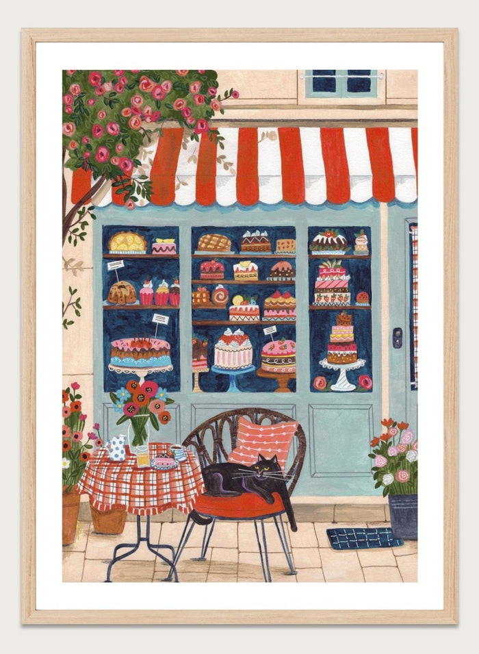 Illustration of a bakery with a cat sitting on a chair outside. Bakery Cat Cafe by Caroline Bonne Müller is a colorful bakery art print featuring cat illustration, pastry shop window, floral details, and modern aesthetic cafe scene.