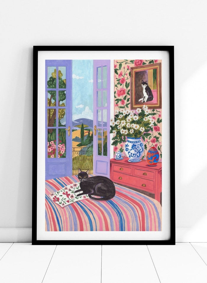Cat lounging on a striped bed with a view of a garden through open doors, surrounded by flowers and decorative items. Black Cat on Bed French Doors Garden View by Caroline Bonne Müller is a colorful interior art print featuring cat illustration, floral room, and scenic garden view in a modern aesthetic style.