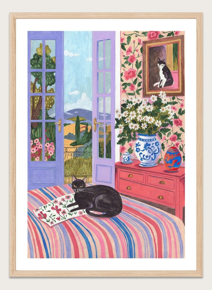 Cat lounging on a striped bed with a view of a garden through open doors, surrounded by flowers and decorative items. Black Cat on Bed French Doors Garden View by Caroline Bonne Müller is a colorful interior art print featuring cat illustration, floral room, and scenic garden view in a modern aesthetic style.