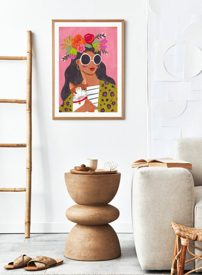 Illustration of a woman with a floral headpiece and sunglasses on a pink background. Cat Lady by Caroline Bonne Müller is a fine art print and wall poster of a woman holding a cat with bold color, floral crown, and modern aesthetic style.