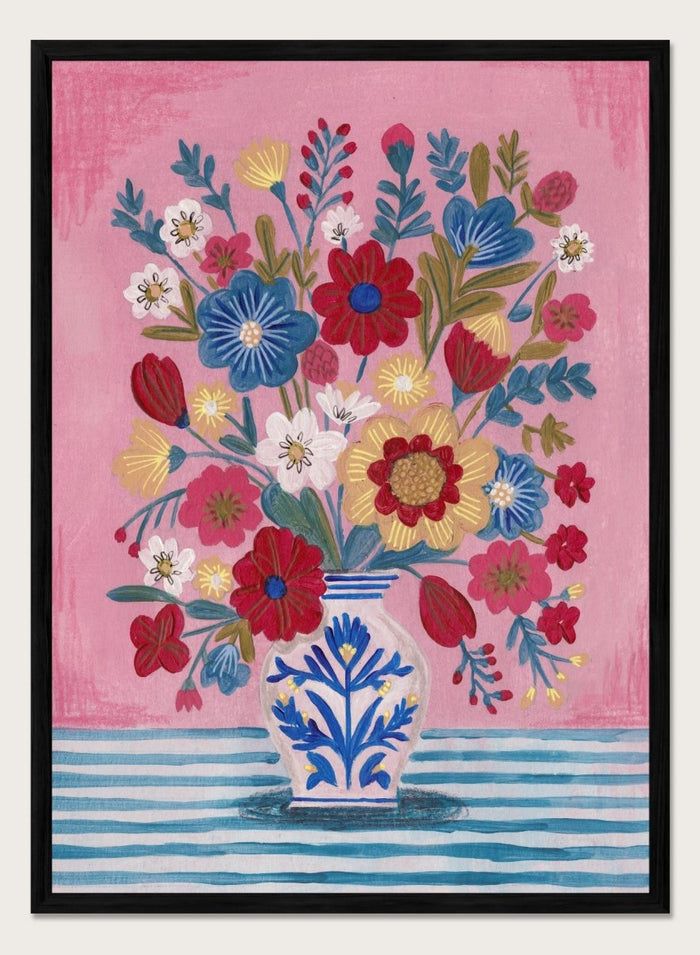 Colorful floral arrangement in a blue and white vase on a pink and blue striped background. Colorful Folk Art Bouquet by Caroline Bonne Müller is a fine art print and wall poster featuring a bright floral arrangement in a patterned vase.